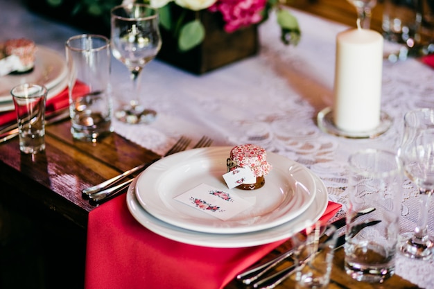 Table de fête avec assiettes fourchettes, couteaux, verres, serviettes et bougie