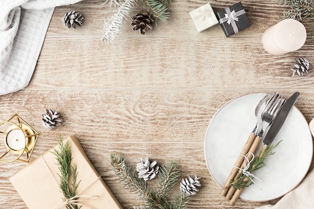 Table de fête en bois avec décorations d'hiver, couverts, bougies et cadeaux. Vue de dessus, mise à plat. Le concept d'un dîner de Noël en famille.