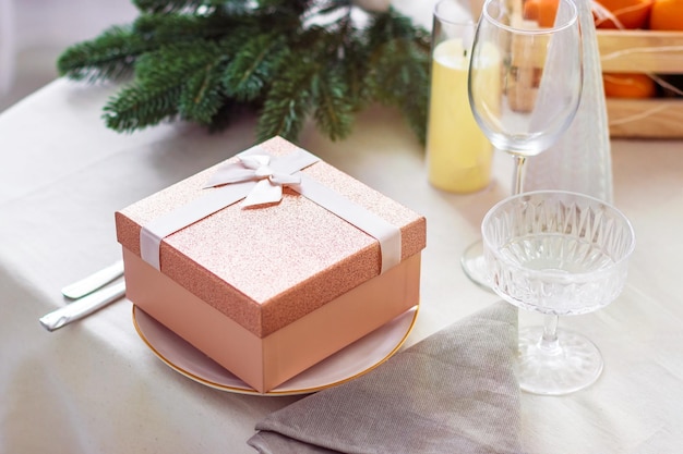 Table de fête avec boîte-cadeau rose dans une assiette sur la table. Vue de côté. Concept de Noël ou du nouvel an