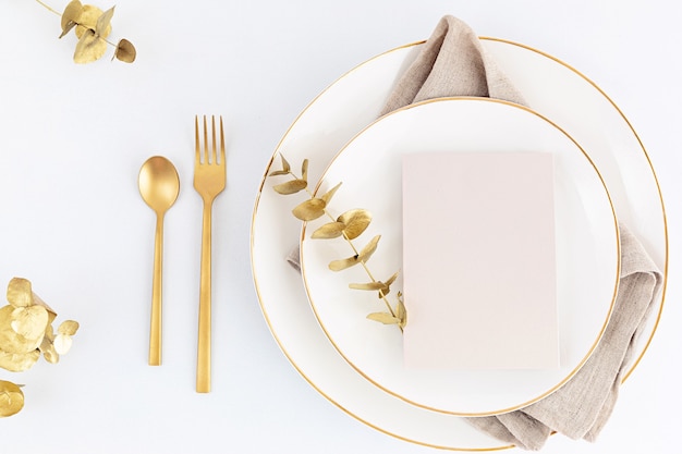 Table de fête avec couverts dorés et assiette en porcelaine