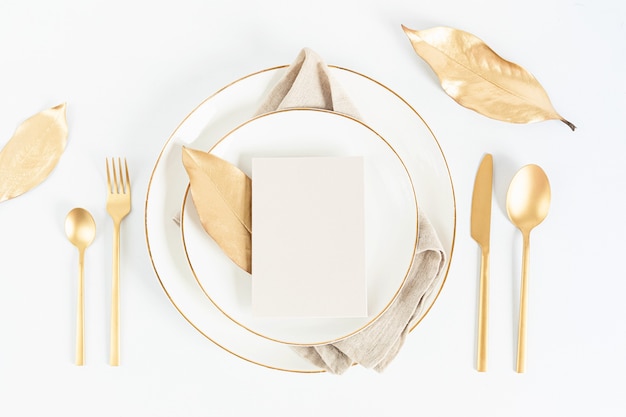 Table de fête avec couverts dorés et assiette en porcelaine