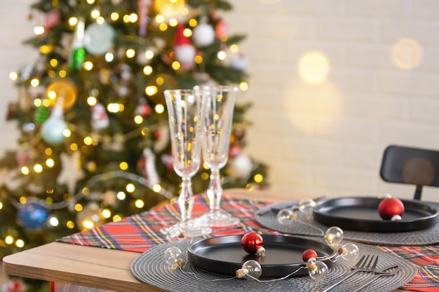 Table de fête dressée dans le salon pour Noël et le Nouvel An dans un style loft Sapin de Noël assiettes et fourchettes noires serviettes tissées vaisselle à la mode intérieur confortable de la maison