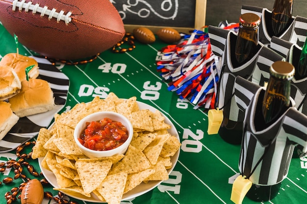 Table de fête de football le jour du match avec bière, frites et salsa.