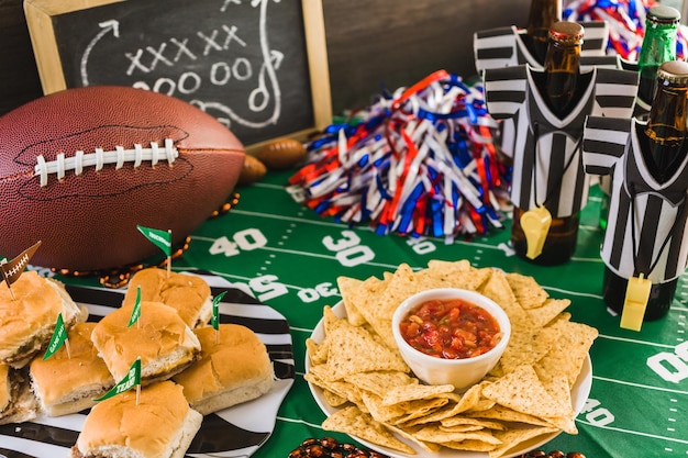 Table de fête de football le jour du match avec bière, frites et salsa.