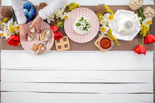 Table de fête de Pâques avec gâteau de Pâques fait maison, thé, fleurs et détails de décoration copiez l'espace. Concept de fête de famille.