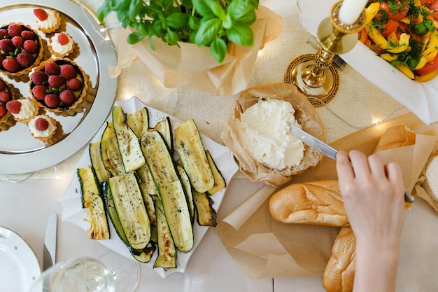 Table de fête servie pour le dîner avec du fromage à la crème du pain frais des courgettes rôties et des tartes aux framboises décorées de bougies