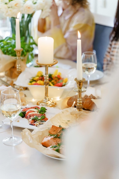 Table de fête servie pour le dîner avec des produits frais et du vin blanc décoré de fleurs et de bougies