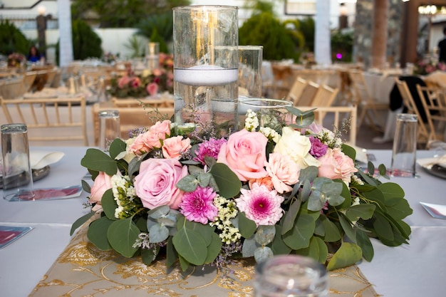 Une table avec un grand centre de table composé de roses roses et blanches et de feuilles vertes