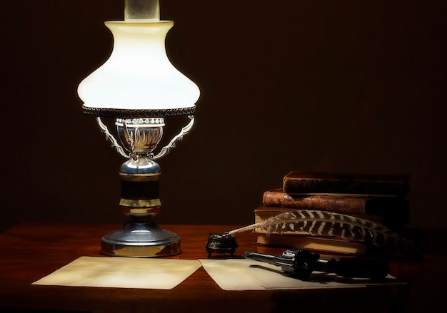 Sur la table il y a une lampe de vieux livres et un stylo avec un encrier