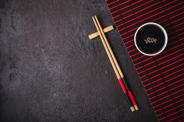 Photo table japonaise disposée de baguettes de bambou et de tapis en couleurs rouge et noire
