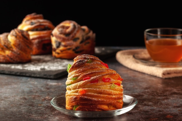 Sur la table, des kraffins aux raisins secs, fruits confits et graines de pavot, saupoudrés de sucre en poudre.