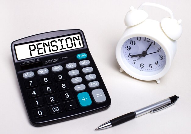 Sur La Table Lumineuse, Il Y A Une Calculatrice Noire Avec Le Texte Pension Sur Le Tableau De Bord, Un Stylo Et Un Réveil Blanc. Concept D'entreprise