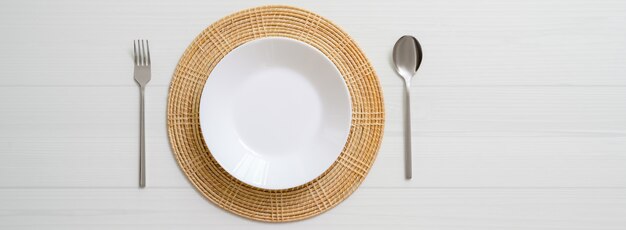 Table à manger en planche blanche avec plaque en céramique blanche sur napperon et argenterie