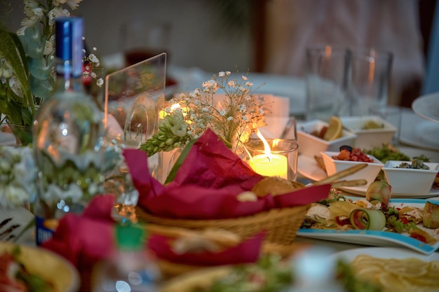 Table de mariage avec bougies nappe blanche divers aliments et fleurs mise au point sélective