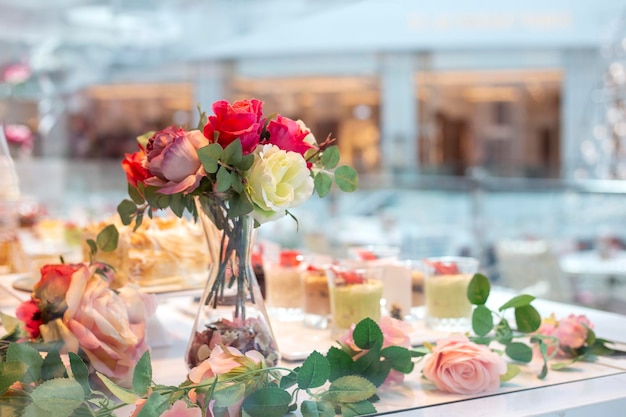 Table de mariage avec desserts décorés de roses artificielles. Table de fête au décor floral