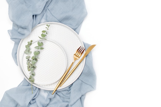 Table de mariage ou de fête. Assiettes et couverts avec textile décoratif gris sur fond blanc. Belle disposition.