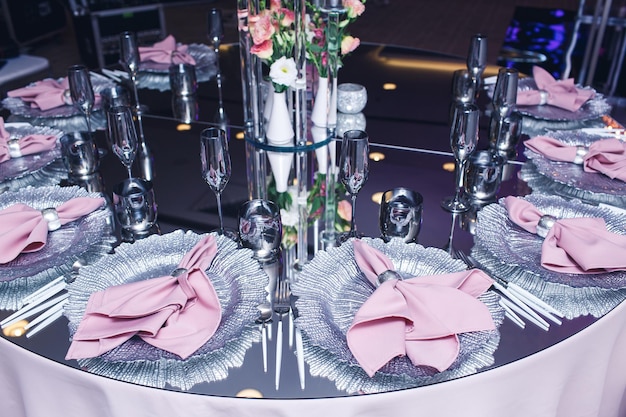 Une table miroir chic servie dans un restaurant Des serviettes roses sur des assiettes argentées