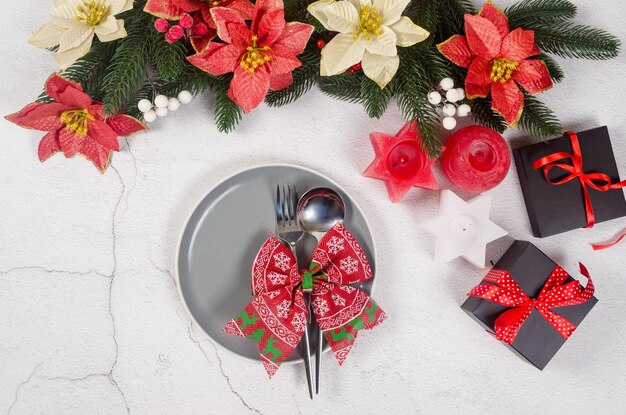 Table de Noël avec assiette grise vide et décorations rouges