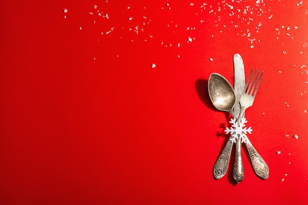 Table de Noël dans les tons rouges avec couverts vintage. Décor festif du Nouvel An, modèle de carte. Lumière dure moderne, ombre sombre. Mise à plat, fond rouge, vue de dessus