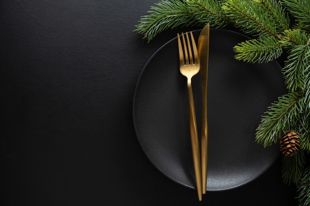 Table de Noël servie dans des tons sombres avec une déco dorée.