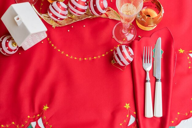 Table de Noël avec tissu rouge et décorations de Noël, couteau et fourchette, verres de champagne