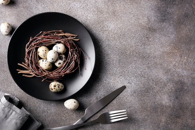 Table de Pâques créative sur une plaque sombre en béton foncé avec un nid avec des œufs sciés