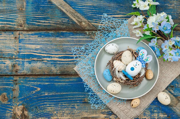 Table de Pâques avec des œufs, un nid d'oiseau et une branche en fleurs