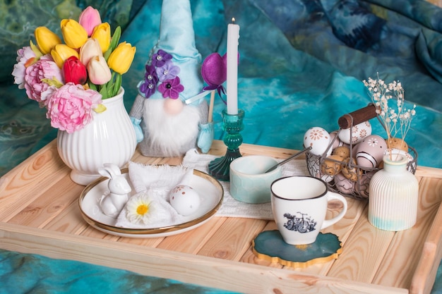 Table de Pâques romantique avec des bougies une assiette en tricot blanc une tasse avec une boisson Décoration de table avec lapin et oeufs peints