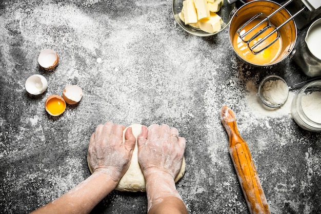 Table de pâte. Femme pétrit la pâte avec divers ingrédients sur la table.