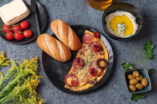 Photo table de petit-déjeuner avec petits pains omelette et tomates cerises