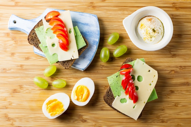 Table de petit-déjeuner avec sandwiches au fromage, légumes, œufs durs et fruits. Vue de dessus