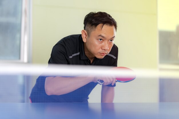 Table de ping-pong, Homme jouant au tennis de table avec raquette et balle dans une salle de sport