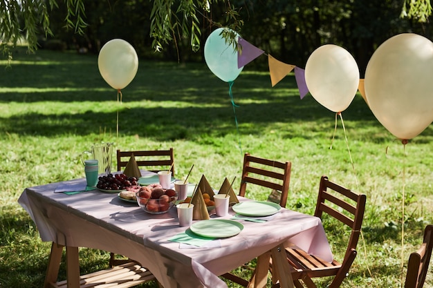 Table de pique-nique d'été à l'extérieur décorée de ballons pour la fête d'anniversaire dans l'espace de copie de la lumière du soleil