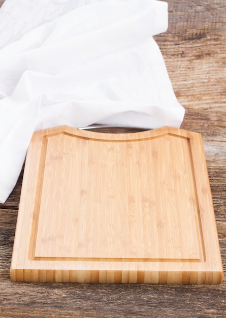 Table avec planche à découper en bois vide et serviette en tissu blanc