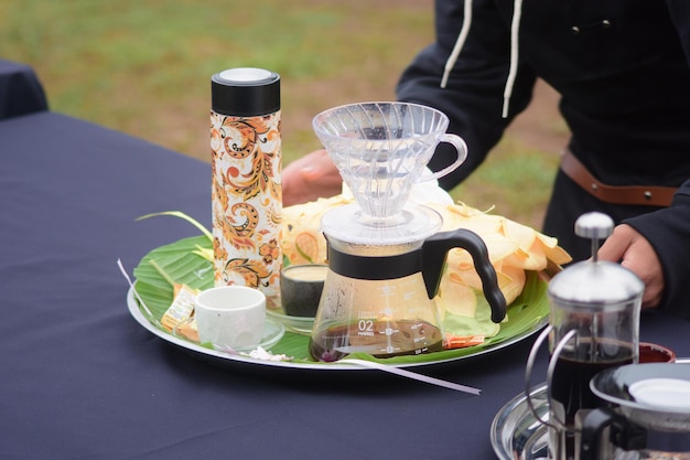 Photo une table avec un plateau de nourriture comprenant une théière, du café et un récipient en verre.