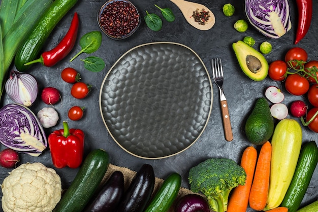 Une table pleine de légumes dont une assiette d'avocat, d'avocat et d'autres légumes.