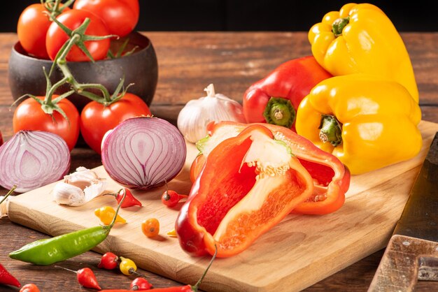 Table avec poivrons rouges et jaunes poivrons oignons et ail et tomates sur bois rustique fond noir mise au point sélective