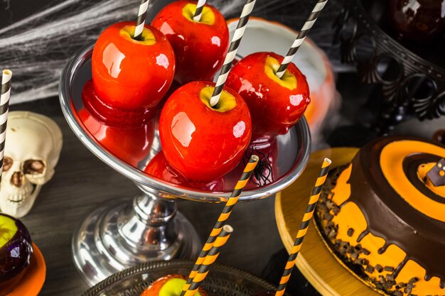 Table avec des pommes de bonbons colorées et un gâteau pour la fête d'Halloween.