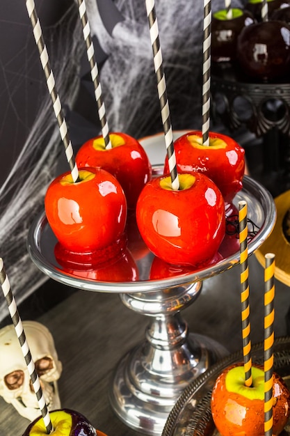 Table avec des pommes de bonbons colorées et un gâteau pour la fête d'Halloween.