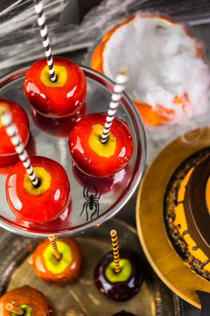 Table avec des pommes de bonbons colorées et un gâteau pour la fête d'Halloween.