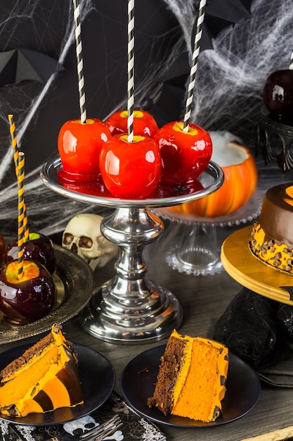 Table avec des pommes de bonbons colorées et un gâteau pour la fête d'Halloween.