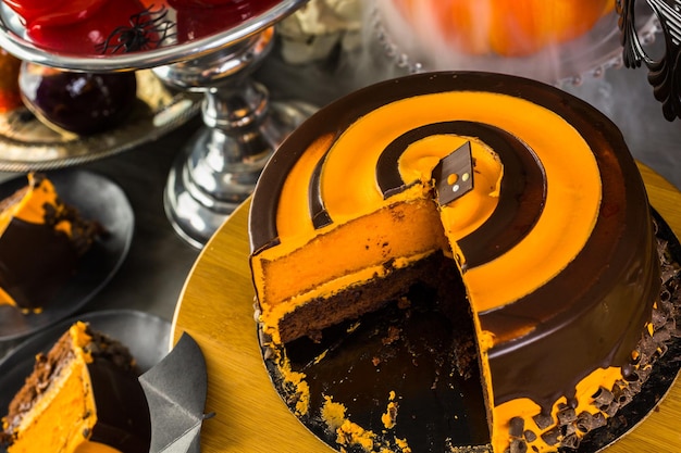 Table avec des pommes de bonbons colorées et un gâteau pour la fête d'Halloween.