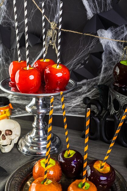 Table avec des pommes de bonbons colorées pour la fête d'Halloween.