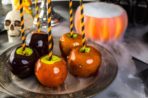 Table avec des pommes de bonbons colorées pour la fête d'Halloween.