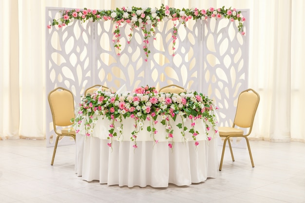 La table principale des jeunes mariés, décorée d'une composition florale et d'un arc aux couleurs pastel