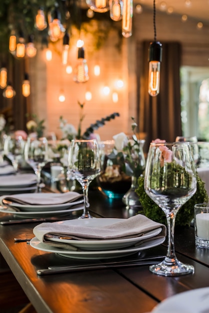 Table de réception de mariage avec ampoules Edison et décor de verdure.