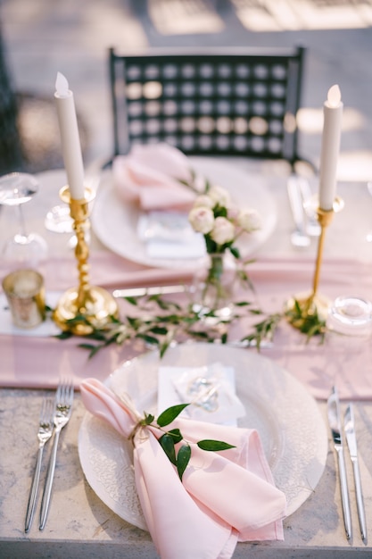 Table de réception de table de dîner de mariage en pierre avec des assiettes roses avec motif et serviettes en chiffon rose