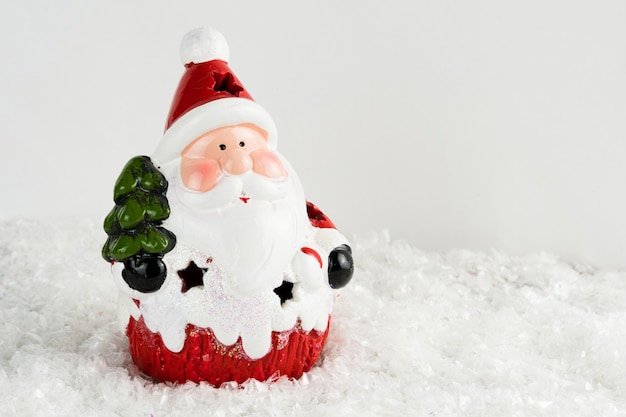 Table recouverte de flocons de neige avec décorations de Noël. Père Noël, arbre de Noël avec des boules rouges et dorées et des lumières. Mise au point sélective.