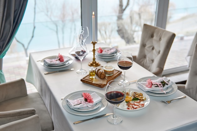 Une table de restaurant décorée avec des verres de vin rouge et un apéritif vous attend