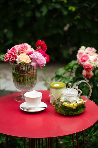 Table Rouge Avec Service à Thé Et Fleurs Dans Le Jardin